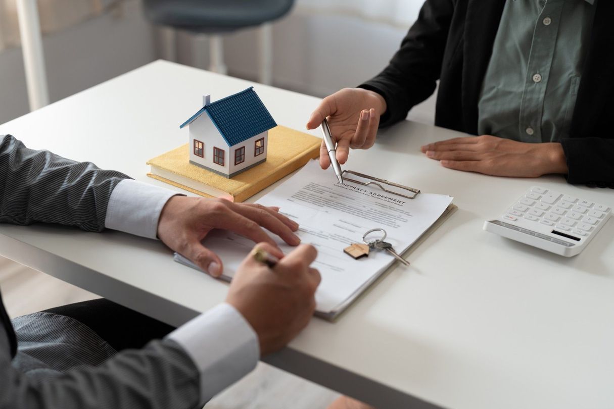 People reviewing a house model and financial documents at a desk