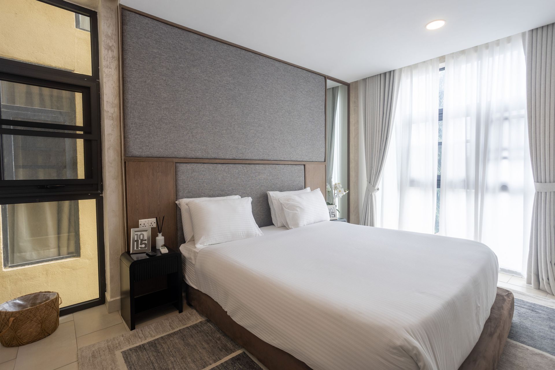 Modern bedroom with a bed, large windows, and neutral decor