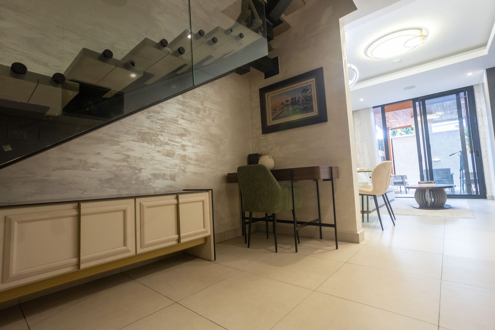 Modern lobby with tiled floor, staircase, benches, and glass entrance doors