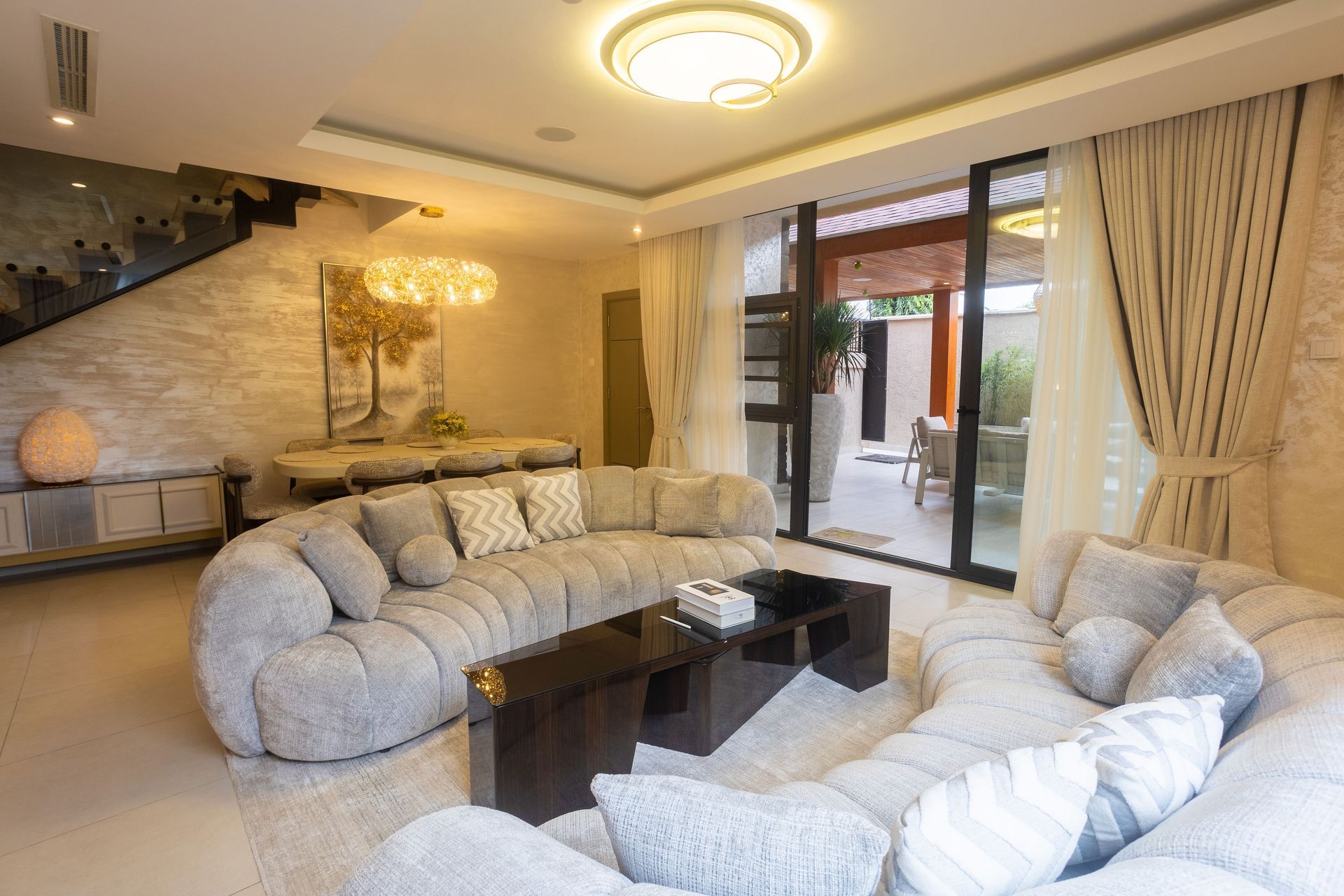 Elegant living room with cream sofas, dark coffee table, marble wall, and glass doors to a patio.