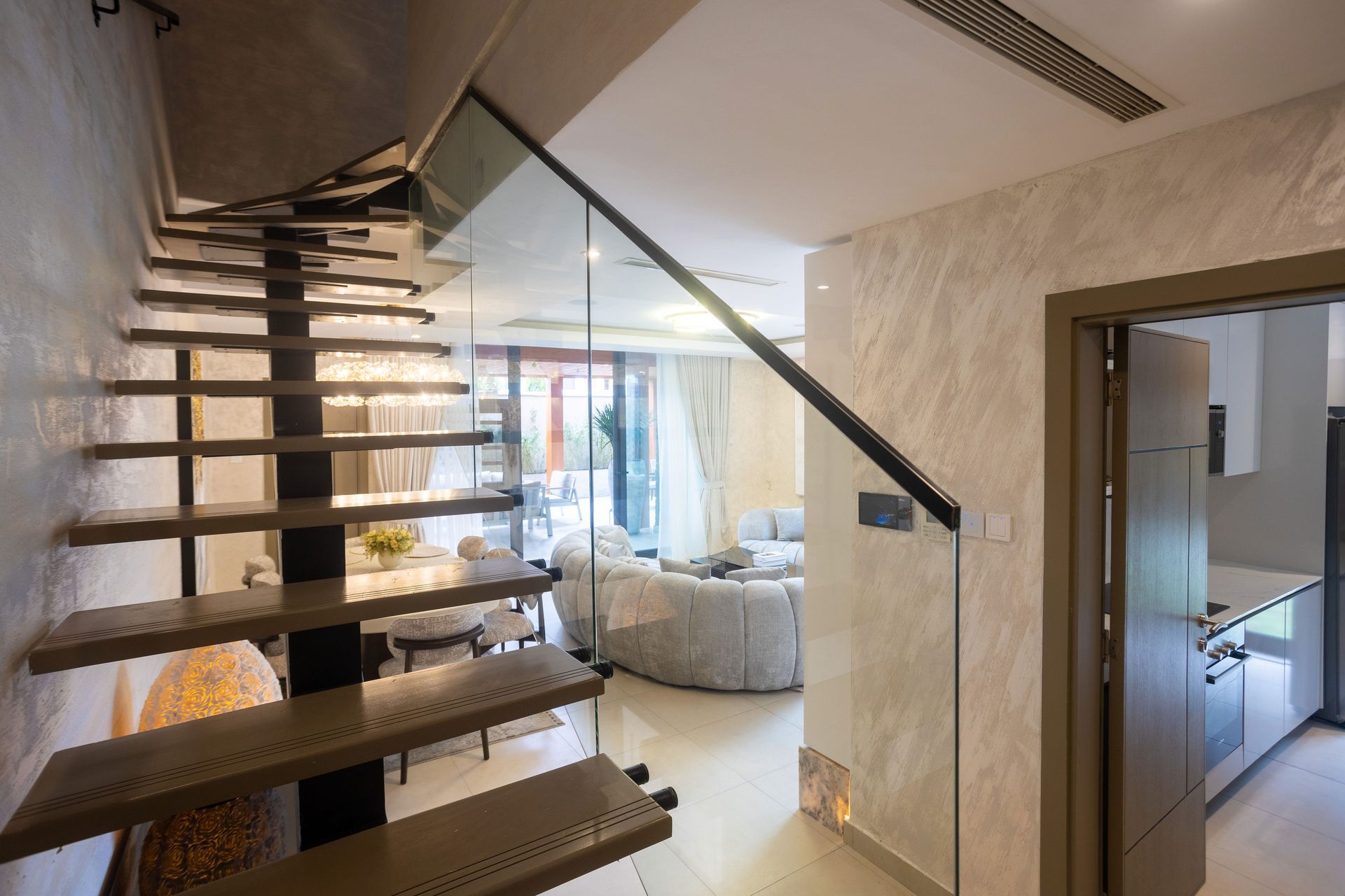 Modern staircase in a bright home, with a view into a living room and kitchen.