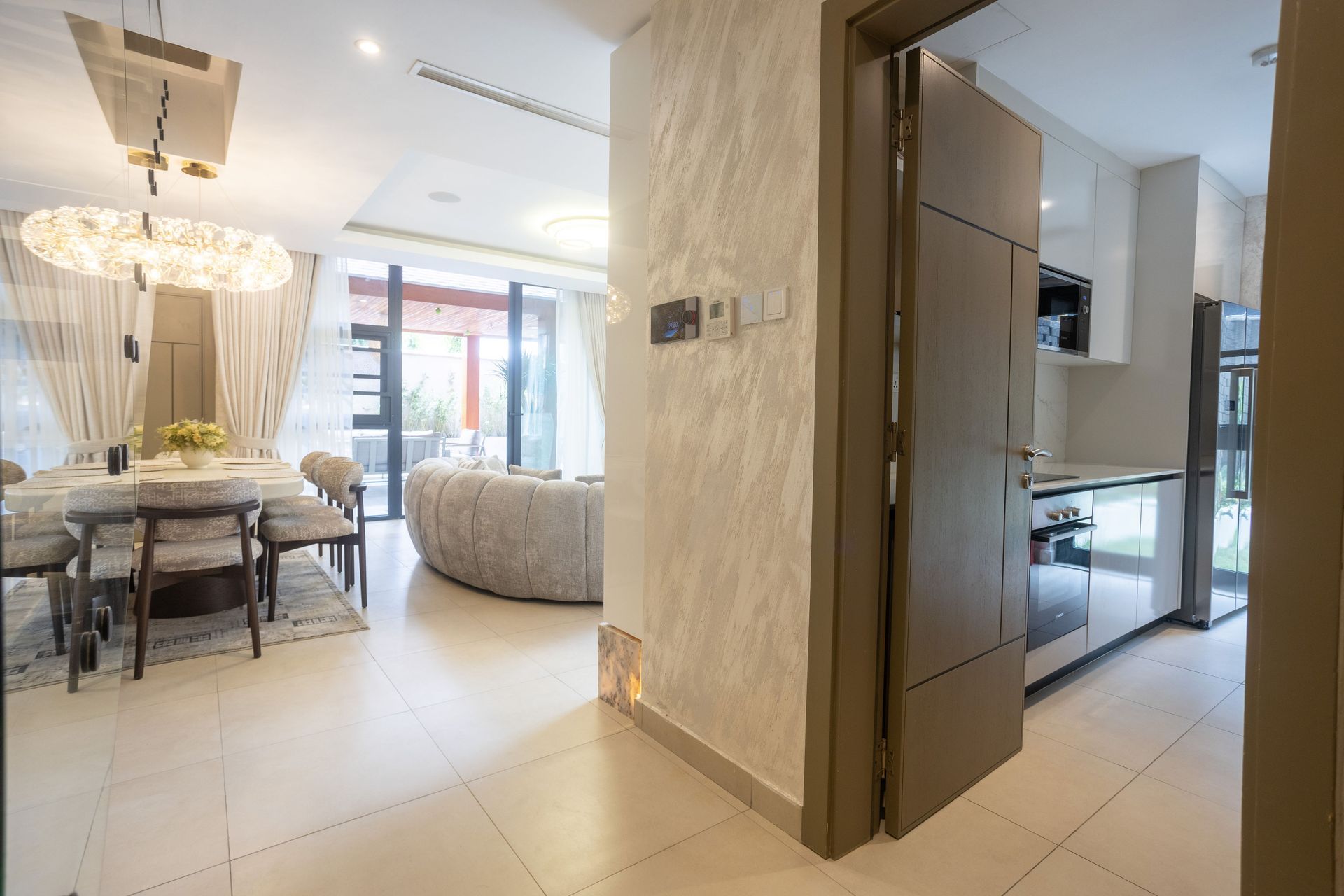Bright modern apartment interior with dining area, sofa, and kitchen visible through an open doorway