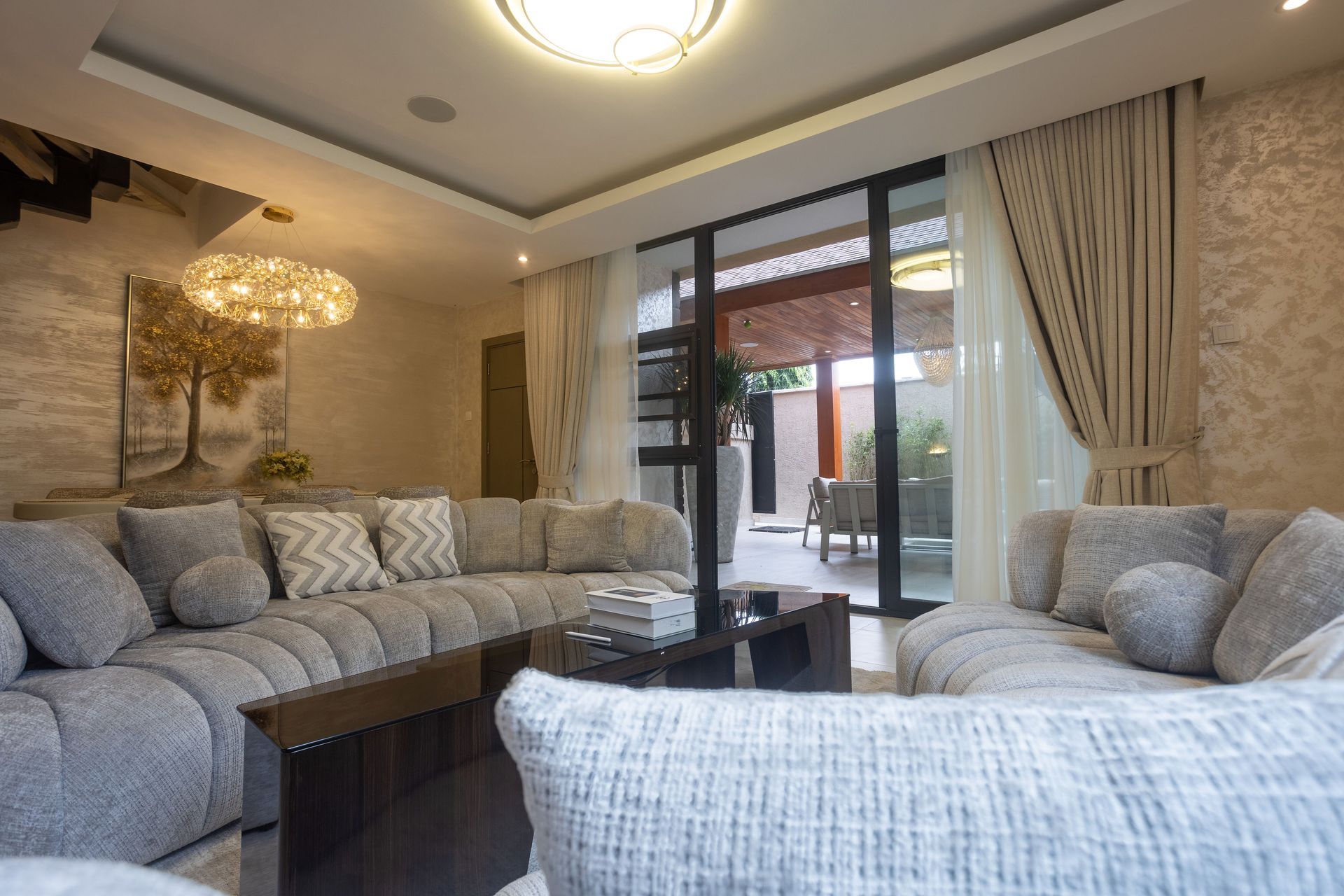 Modern living room with gray sofas, glass coffee tables, and sliding doors to a patio