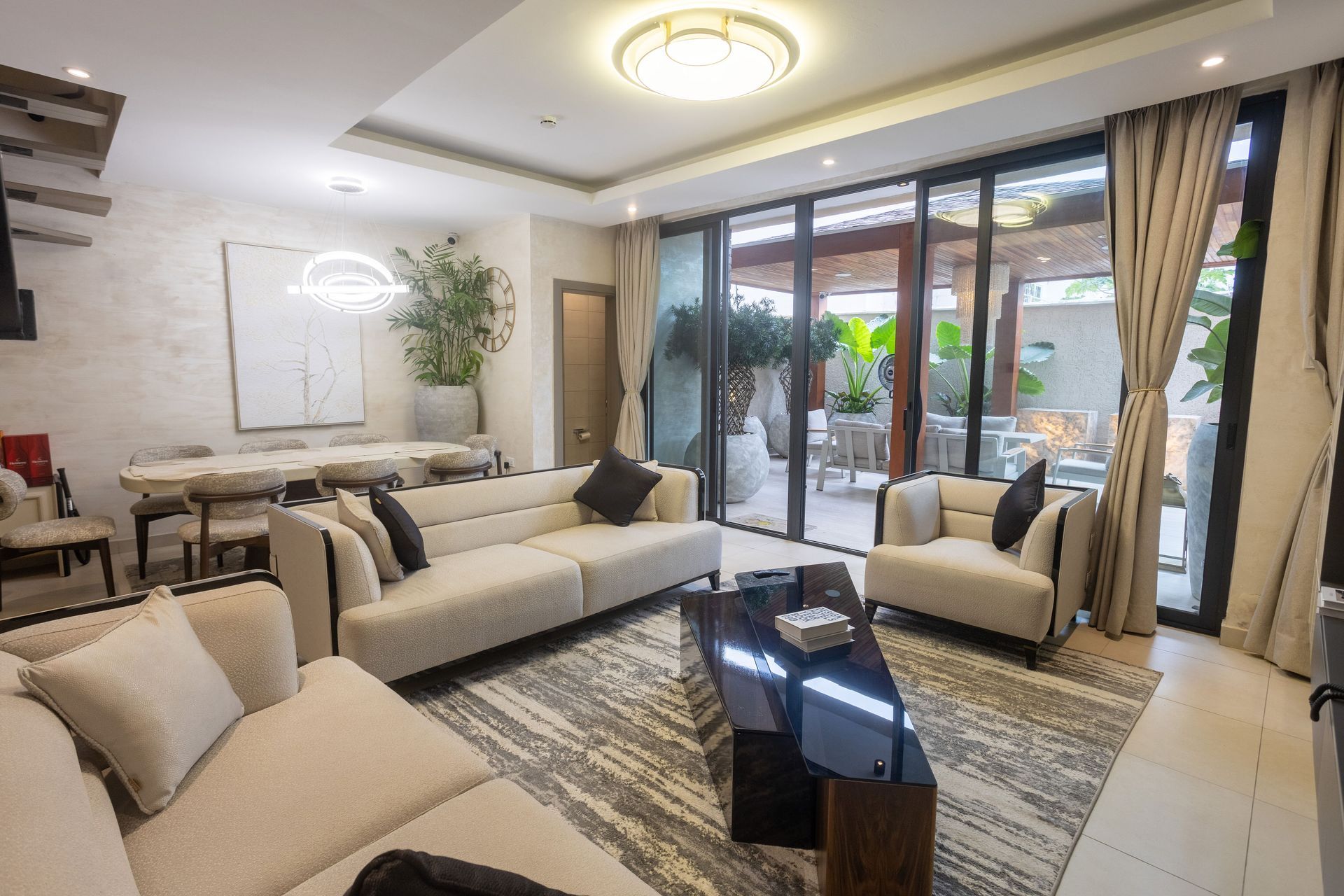 Modern living room with cream sofas, patterned rug, glass coffee table, and large patio doors.