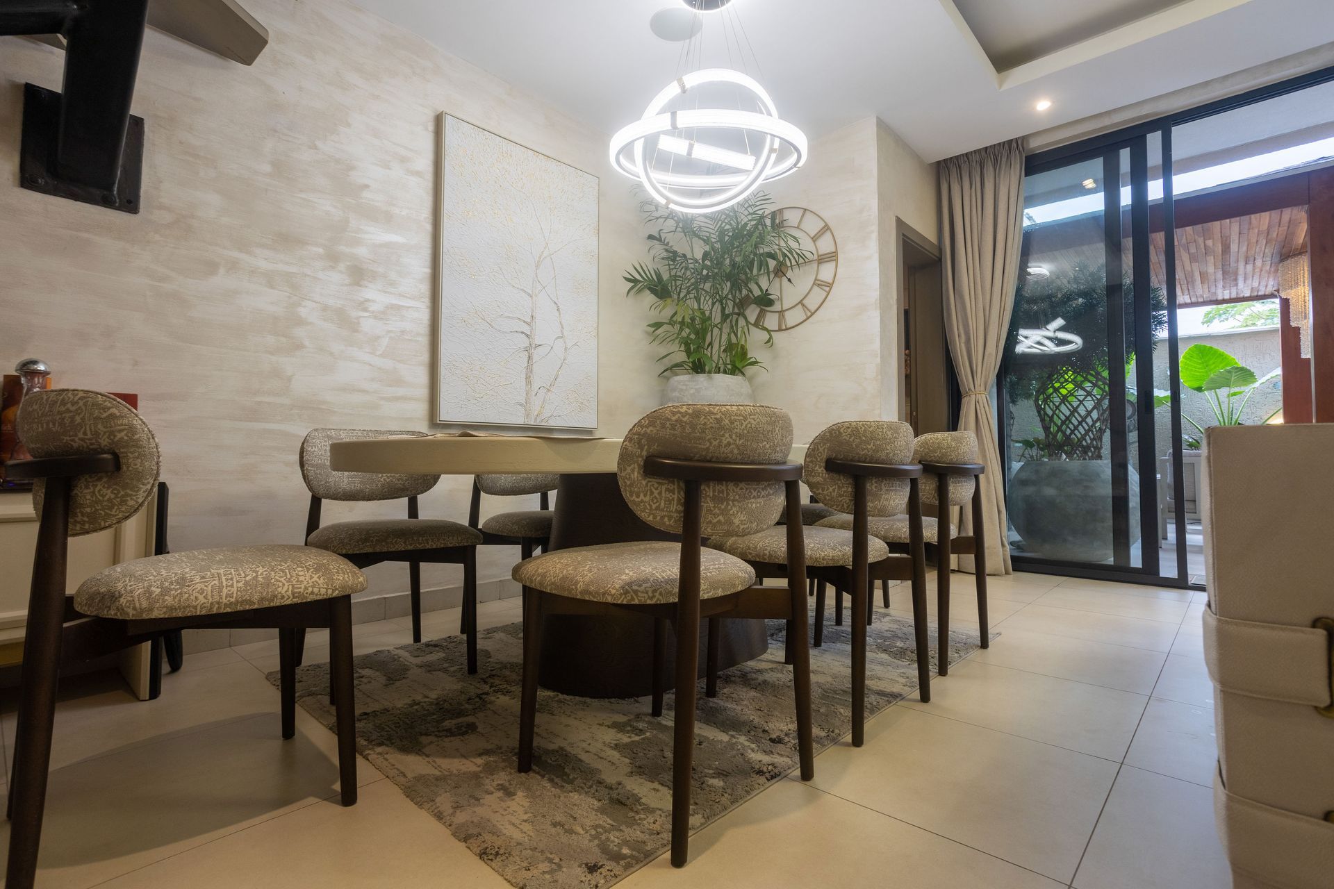 Modern dining room with a round table, upholstered chairs, pendant light, and sliding glass doors