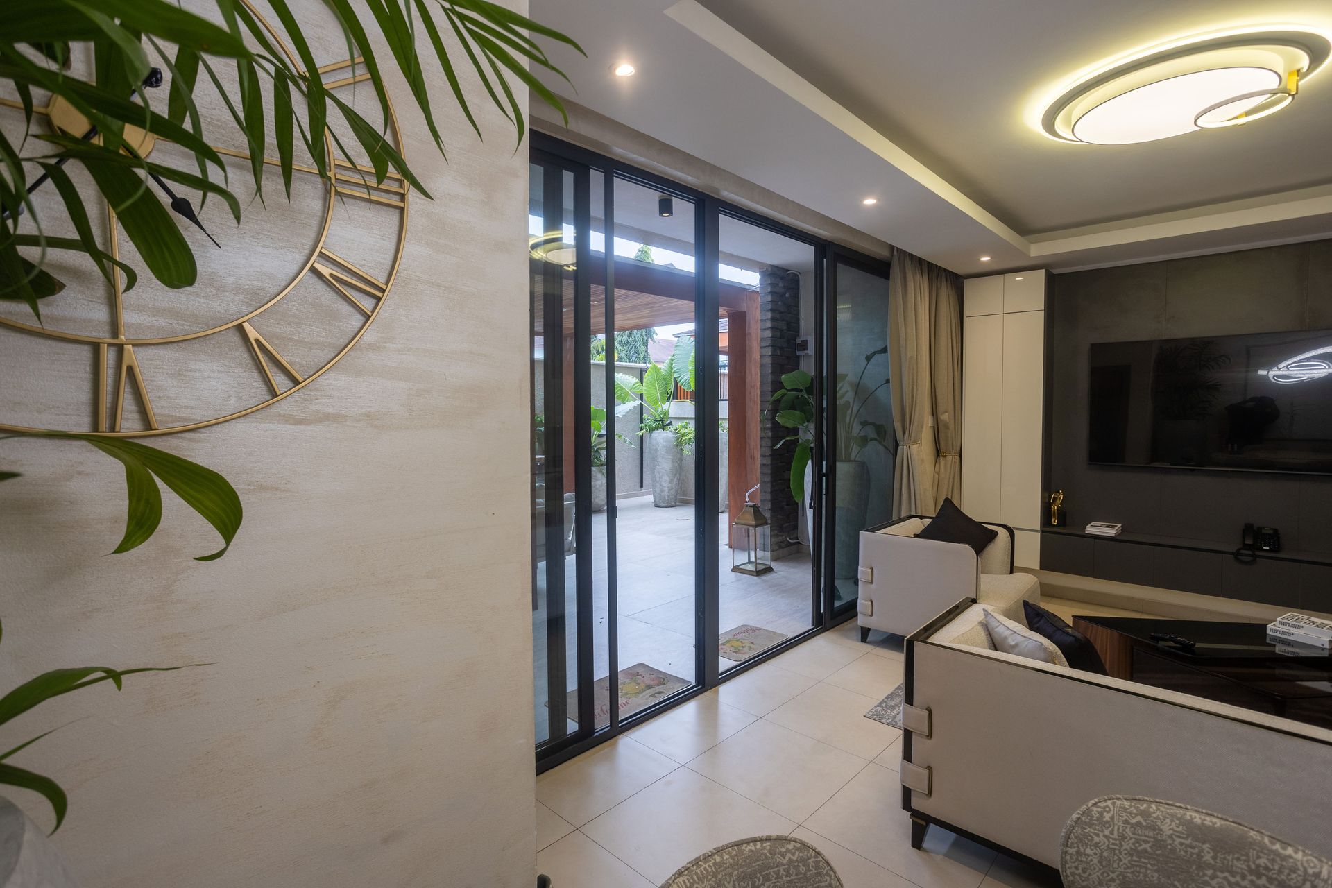 Modern living room with white sofa, wall-mounted TV, and sliding glass doors to a patio