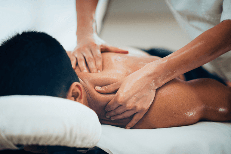 Person receiving a back massage on a spa table with white towels