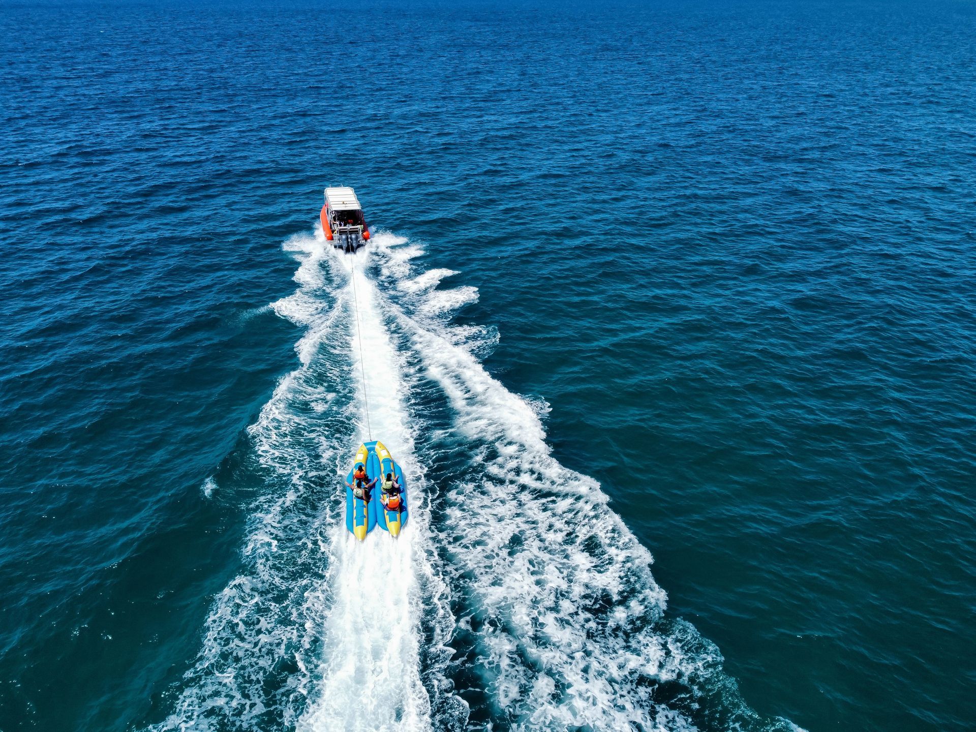 Two boats racing across blue water, leaving white wakes behind them