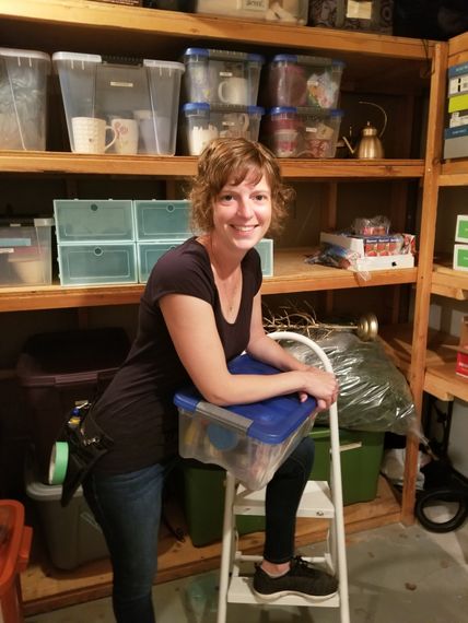 A woman sitting on a ladder holding a blue plastic container