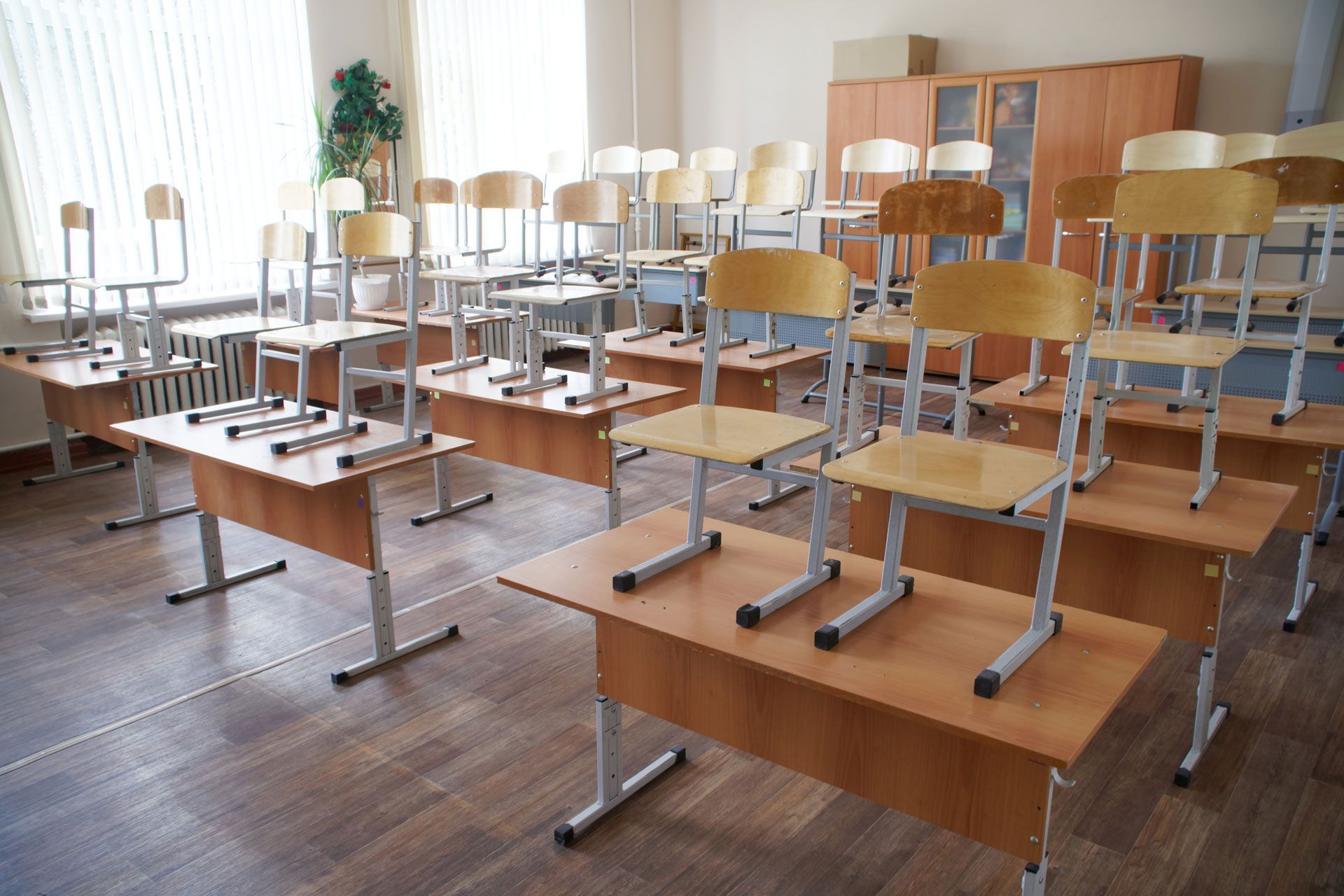 Empty classroom with desks and chairs stacked on top.