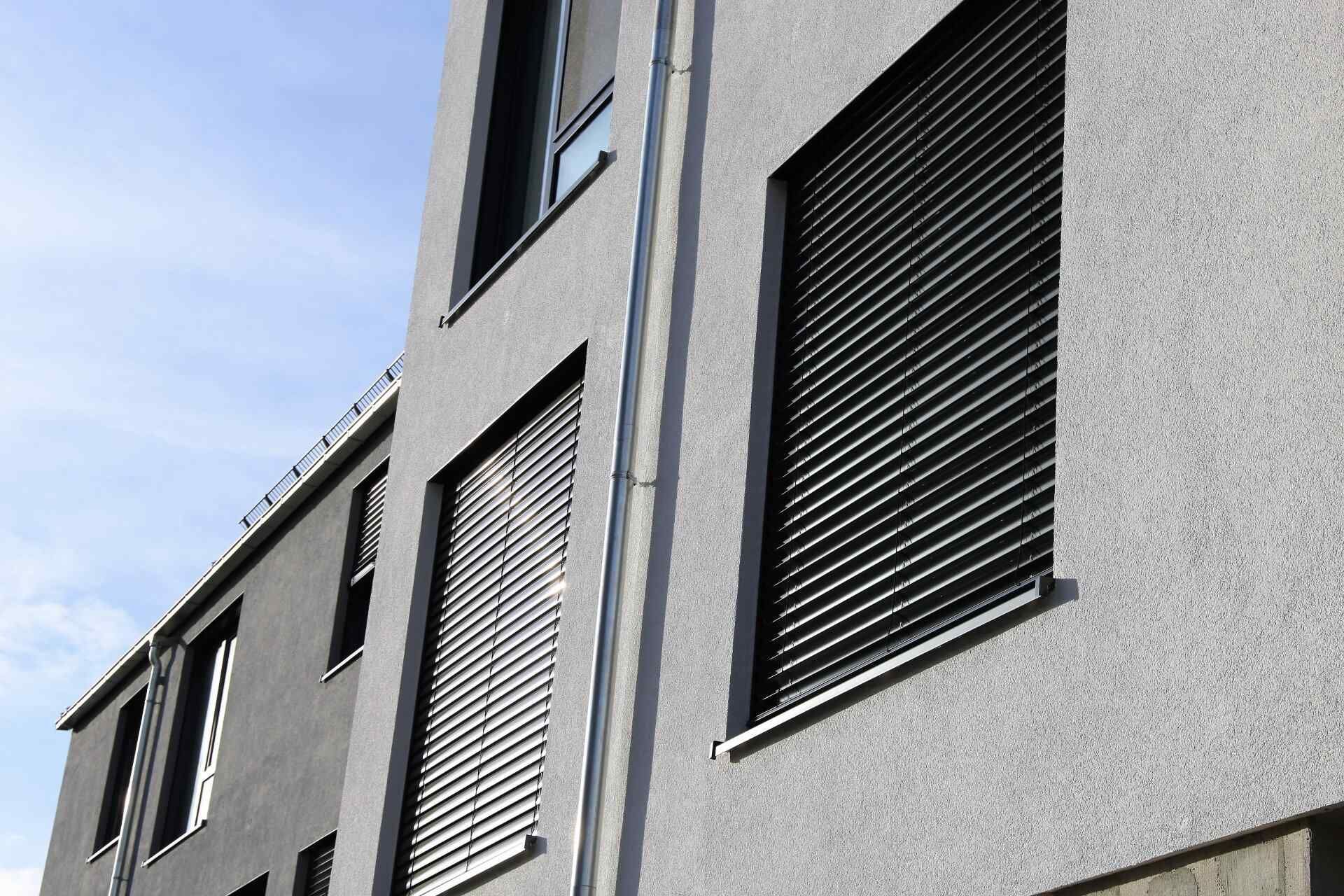 Gray Building With Dark Window Shutters, Against a Blue Sky — Big Tom's Security Screens in Farleigh, QLD