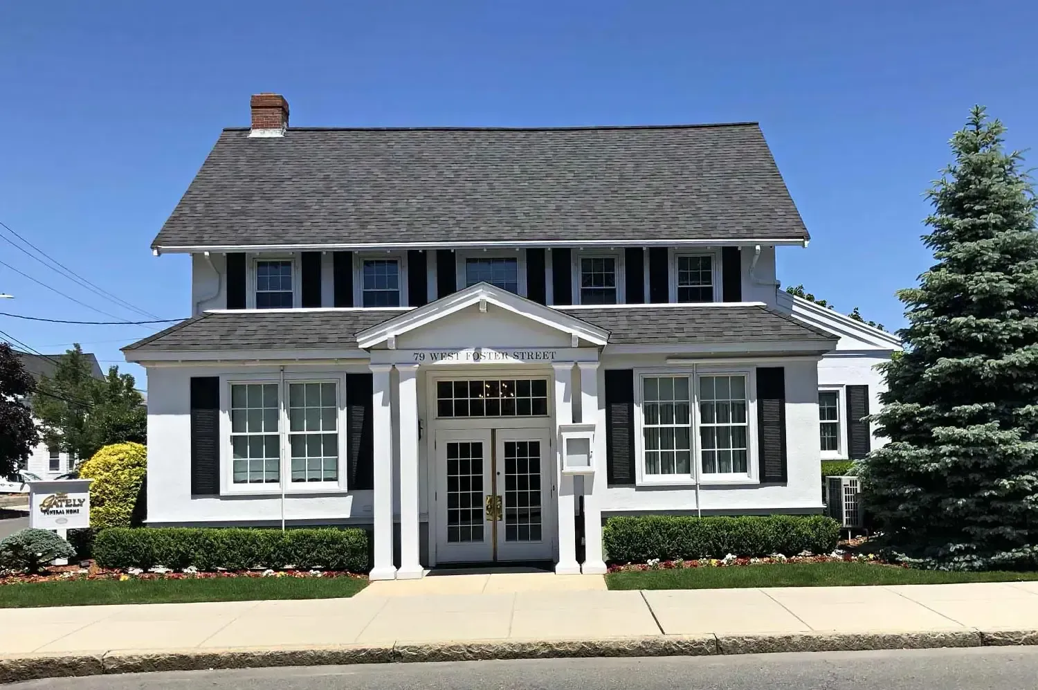 The front door of a house with a porch and plants in front of it.
