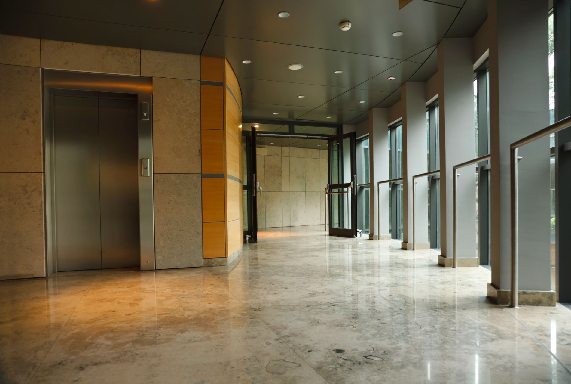 Vista interna dell'atrio di un edificio per uffici con ascensore, porte in vetro e pavimenti in marmo.