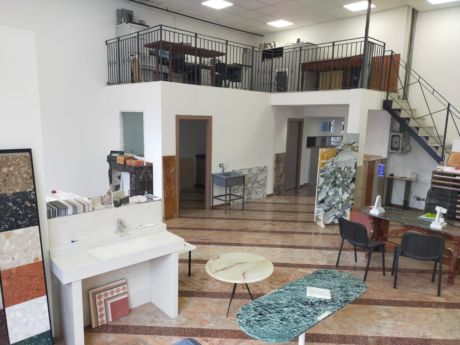 Interno di un negozio di pietre e piastrelle con soppalco e varie esposizioni.