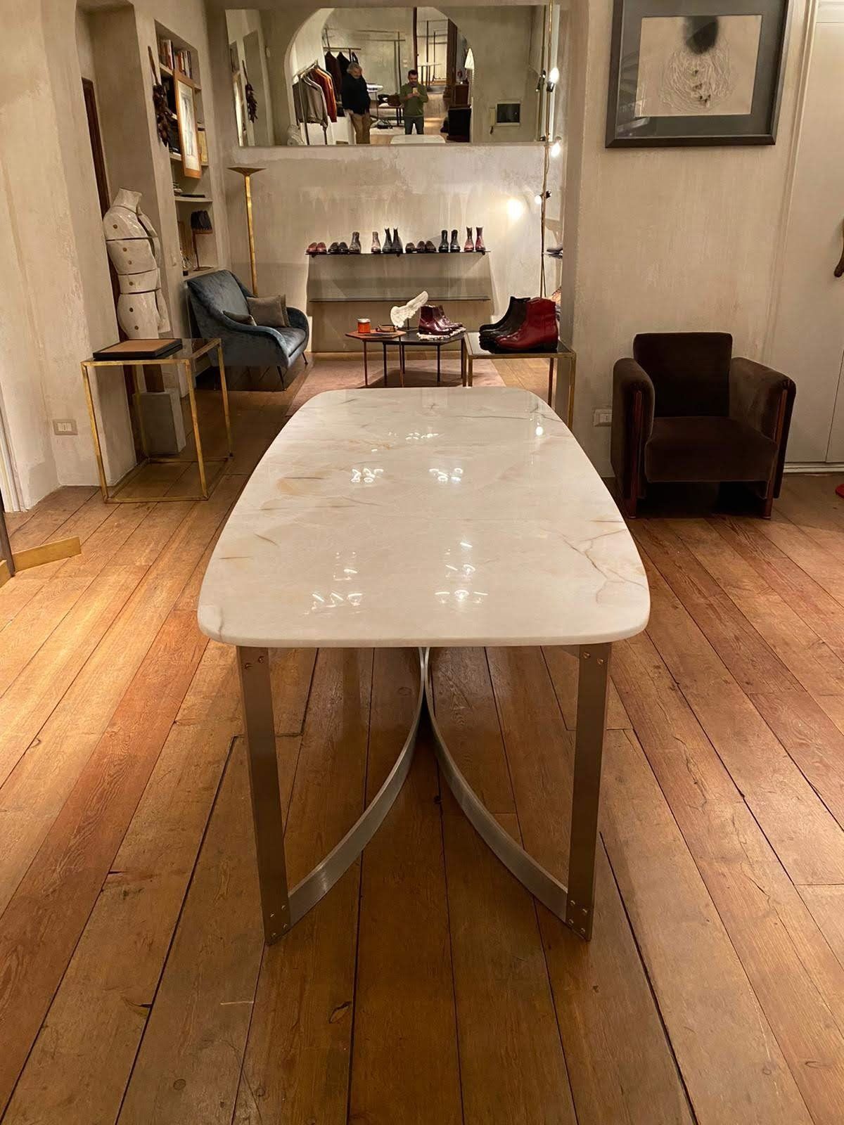 Un tavolo in marmo bianco con gambe in metallo curvato in una stanza con pavimenti e mobili in legno.