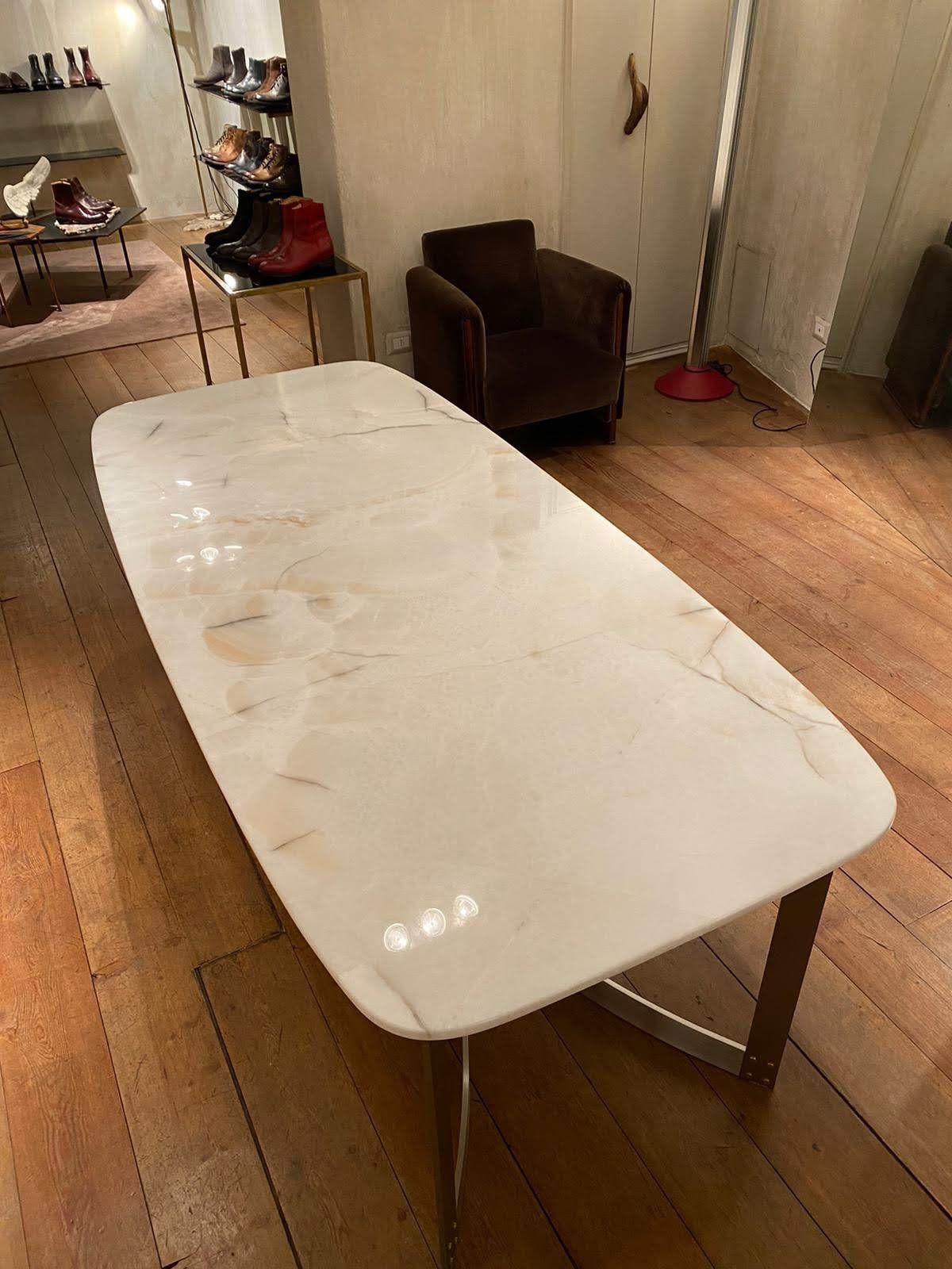 Tavolo con piano in marmo bianco e gambe in acciaio inossidabile, in un negozio al dettaglio con pavimenti in legno.