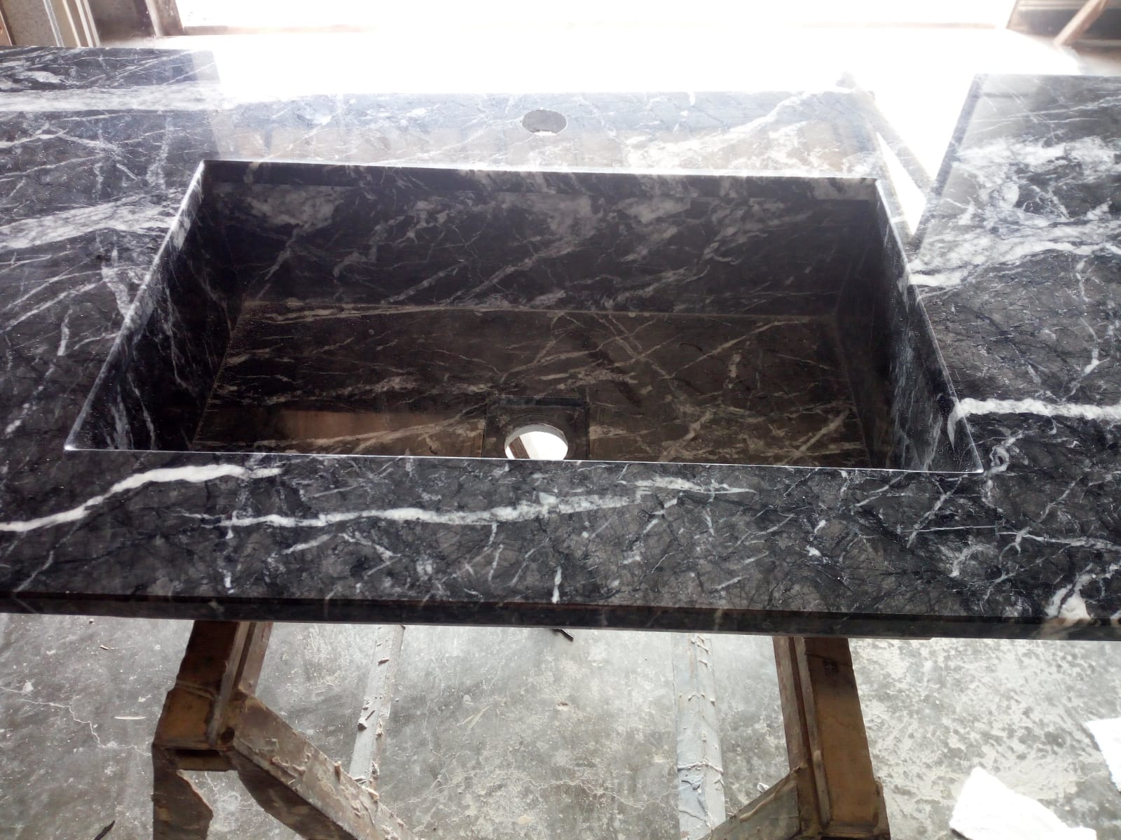 Piano del bagno in marmo nero con lavabo rettangolare e foro per il rubinetto.