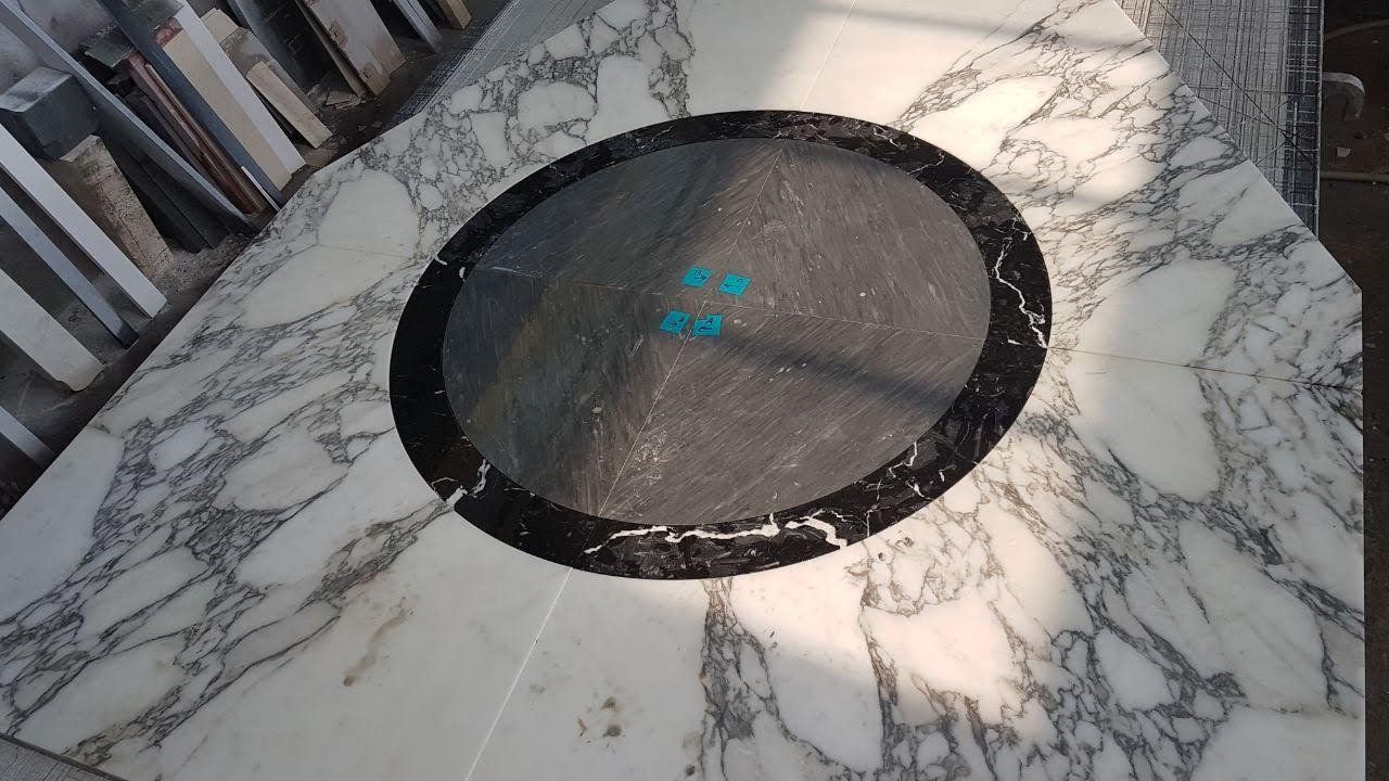 Piano di lavoro in marmo bianco con inserto ovale nero e testo blu.