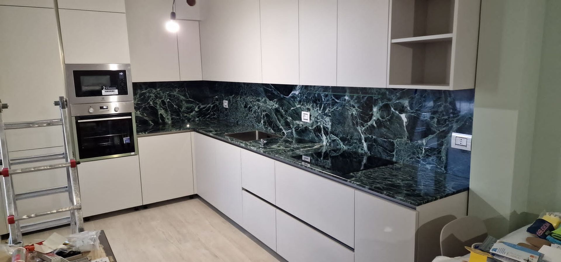 Moderna cucina bianca con paraschizzi in marmo nero ed elettrodomestici in acciaio inossidabile.