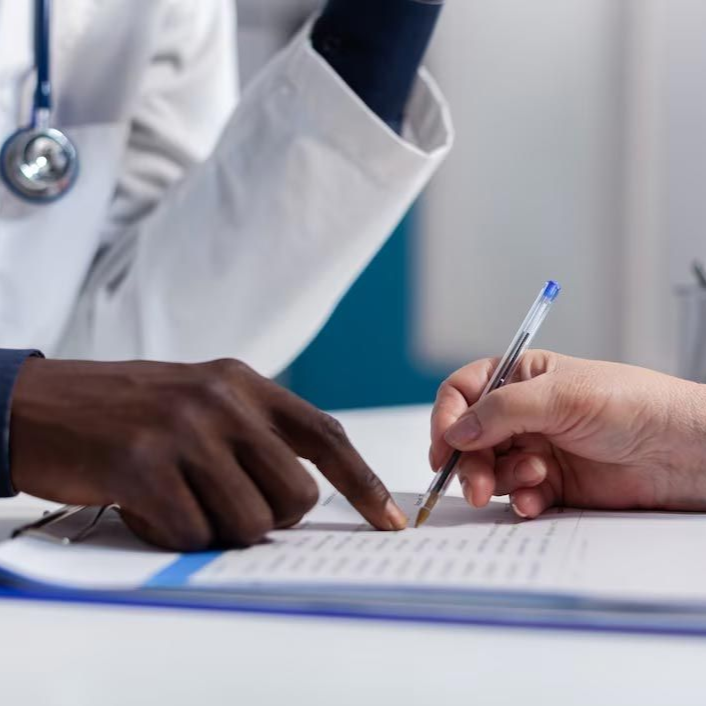 Doctor and patient pointing and signing a form at a desk