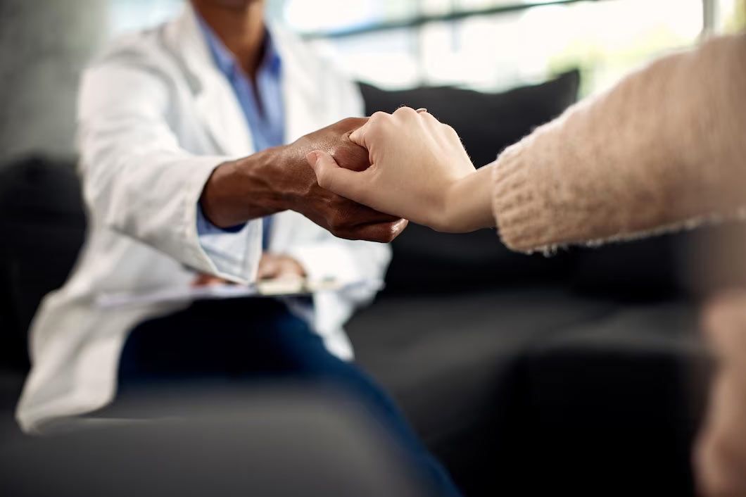 Doctor holding a patient’s hand in a counseling session on a couch
