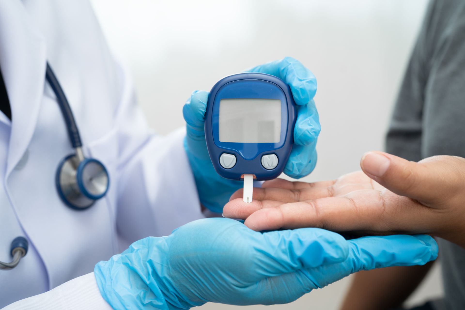 Healthcare worker testing blood sugar with glucometer on patient’s finger