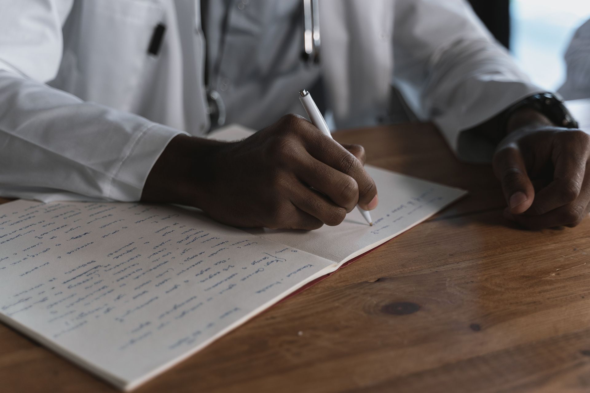 Hands signing a document on a wooden desk in an office setting