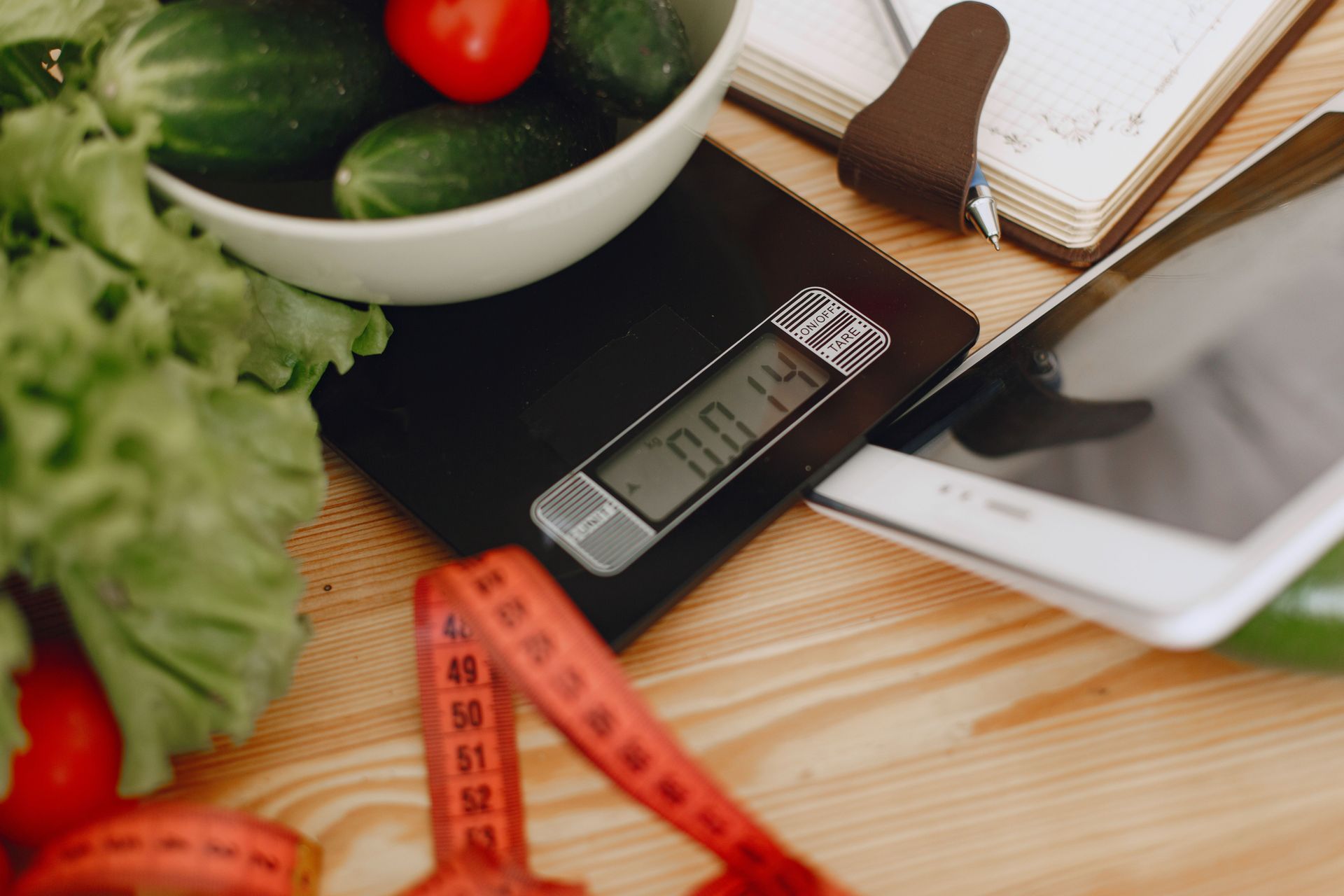 Healthy food and fitness items on a table with a calculator and measuring tape