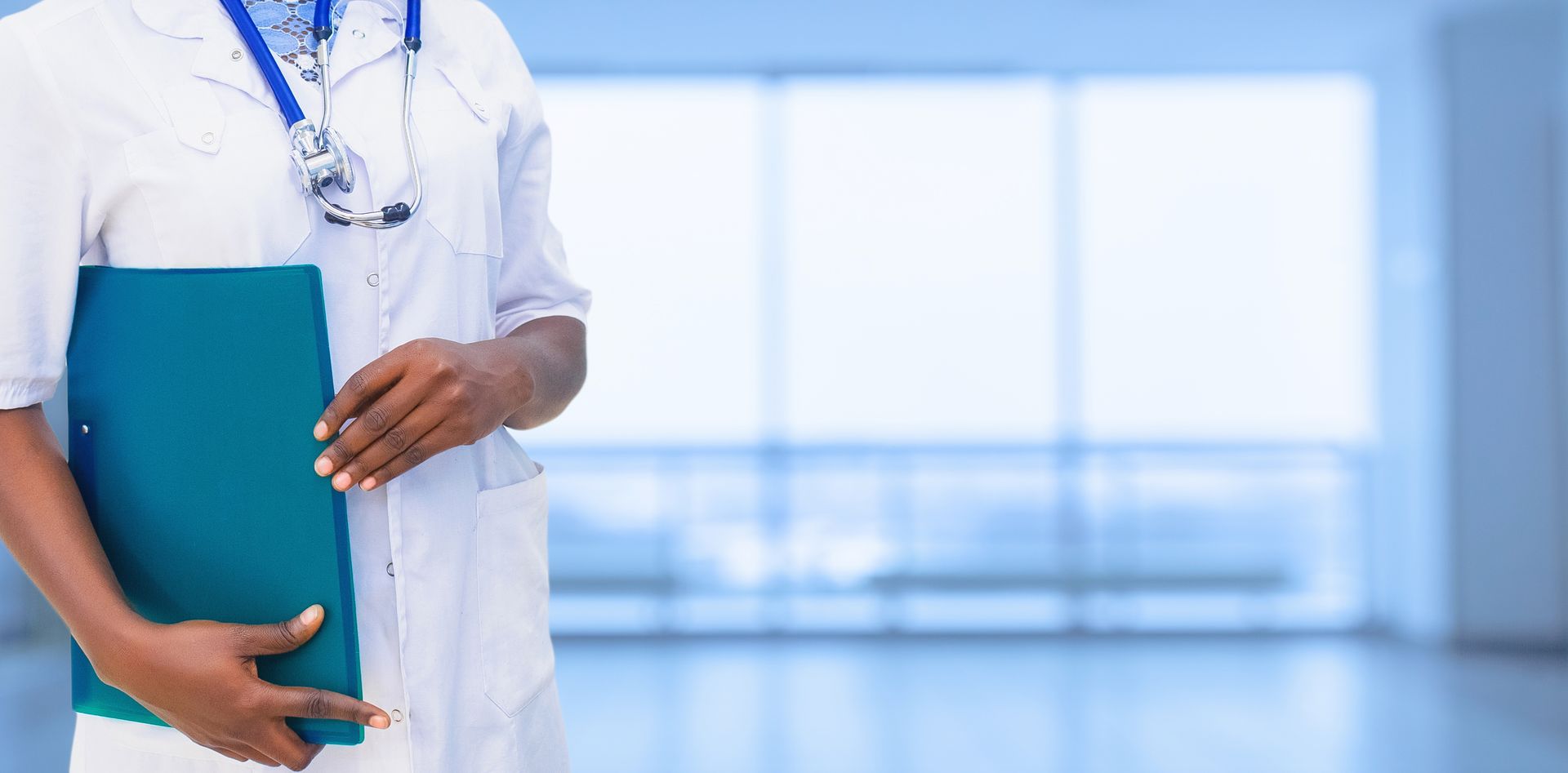 Doctor holding a blue folder in a bright hospital corridor