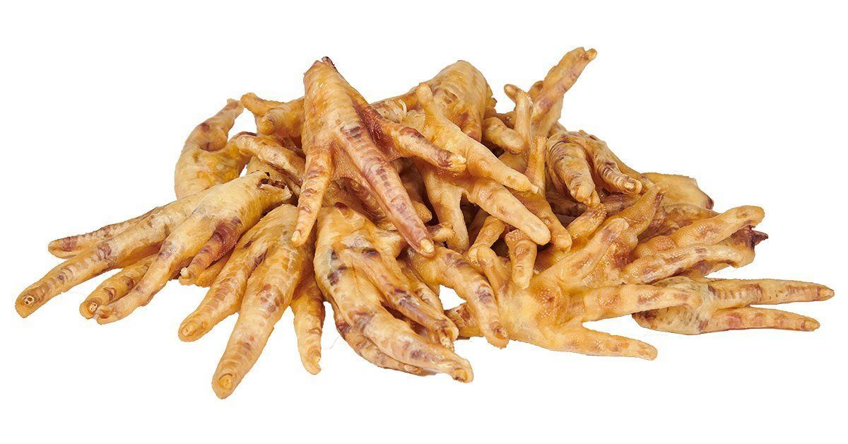 A pile of raw, light-brown chicken feet against a plain white background.