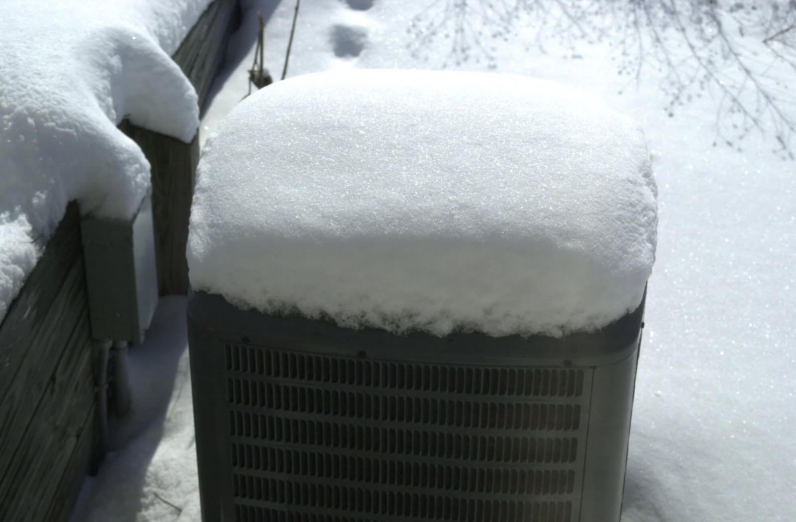 Outdoor air conditioner covered in a thick layer of snow