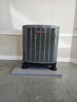 Black floor fan on a tiled patio against a white wall