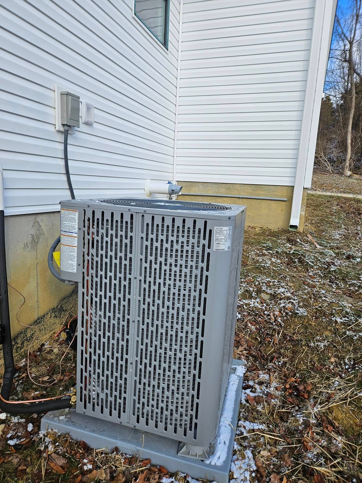 Outdoor HVAC unit beside a white house with a detached front grille and fallen leaves on the ground