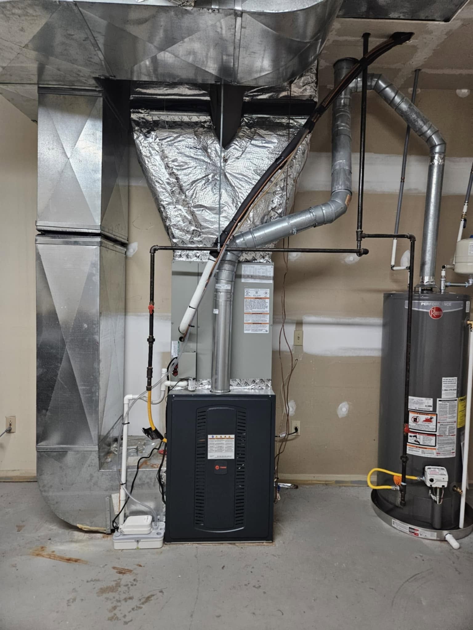 HVAC furnace and ductwork in a utility room beside a water heater and vents