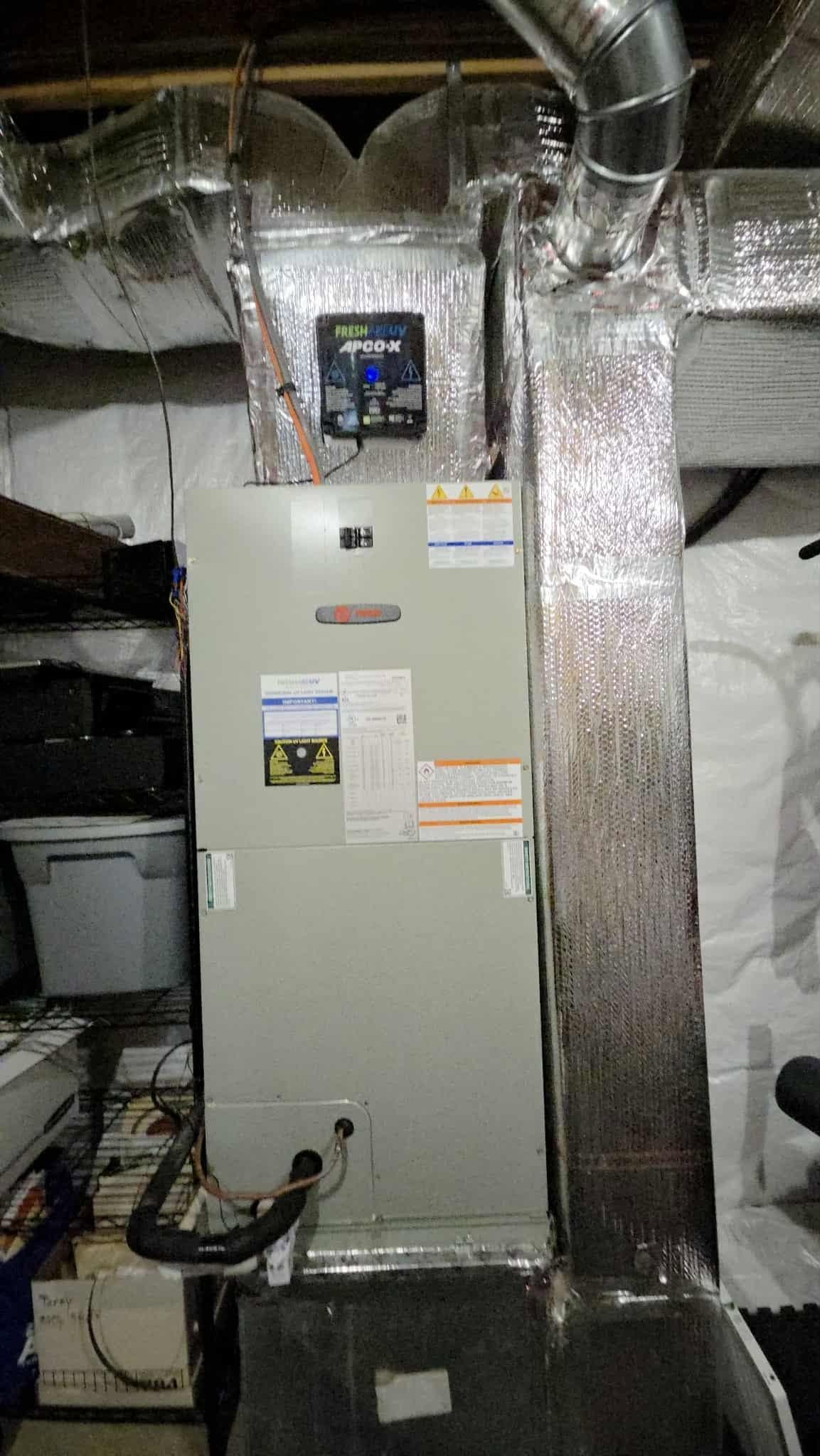 Basement HVAC furnace with insulated ducts and foil-wrapped pipes in a utility room