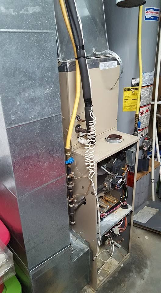 Open HVAC furnace with exposed wiring and ductwork in a utility room.