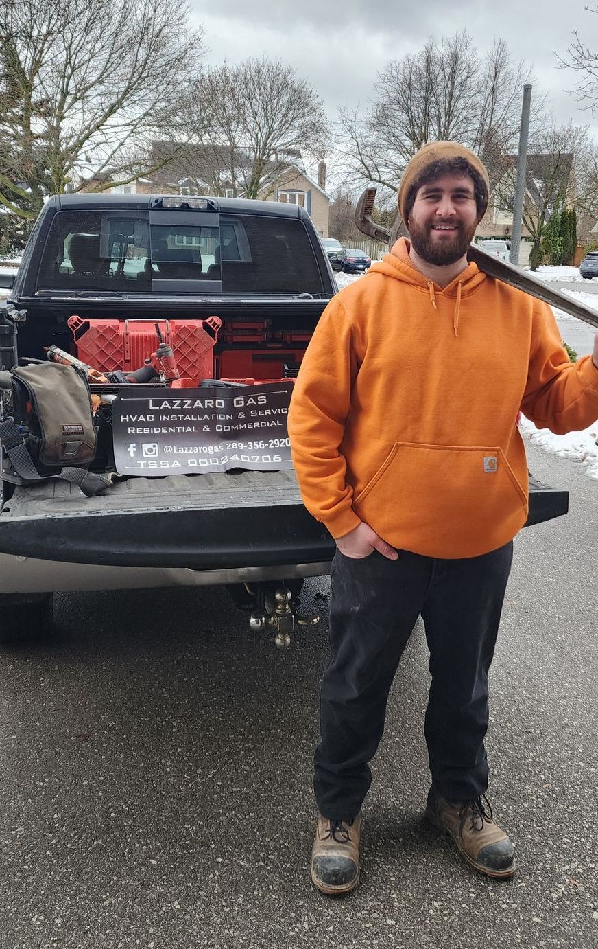 A man in an orange hoodie is standing in front of a truck.