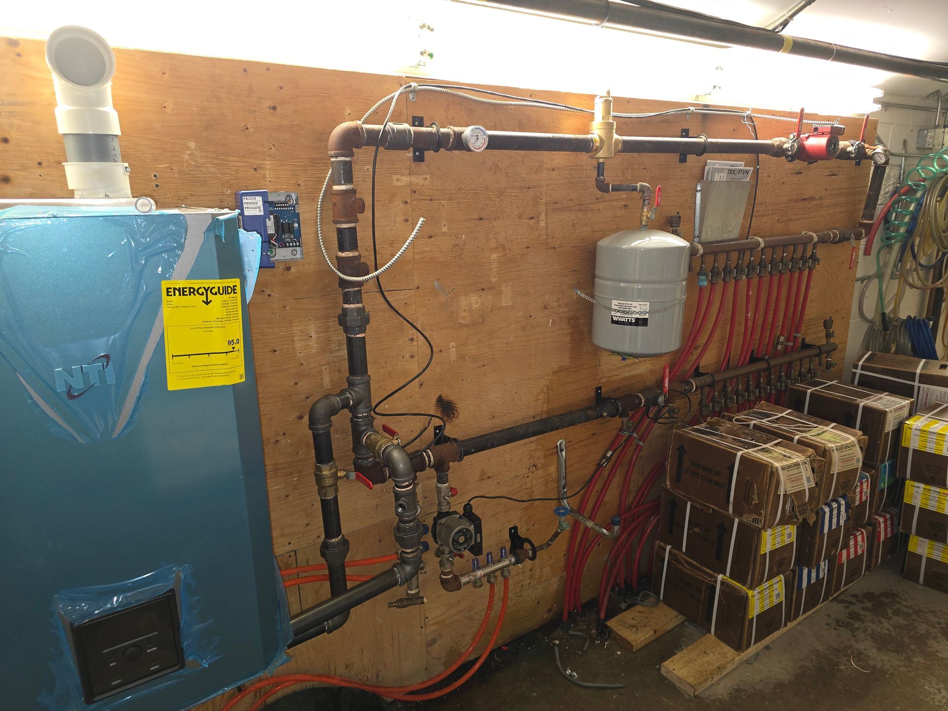 A blue boiler is sitting in a room next to a wall.