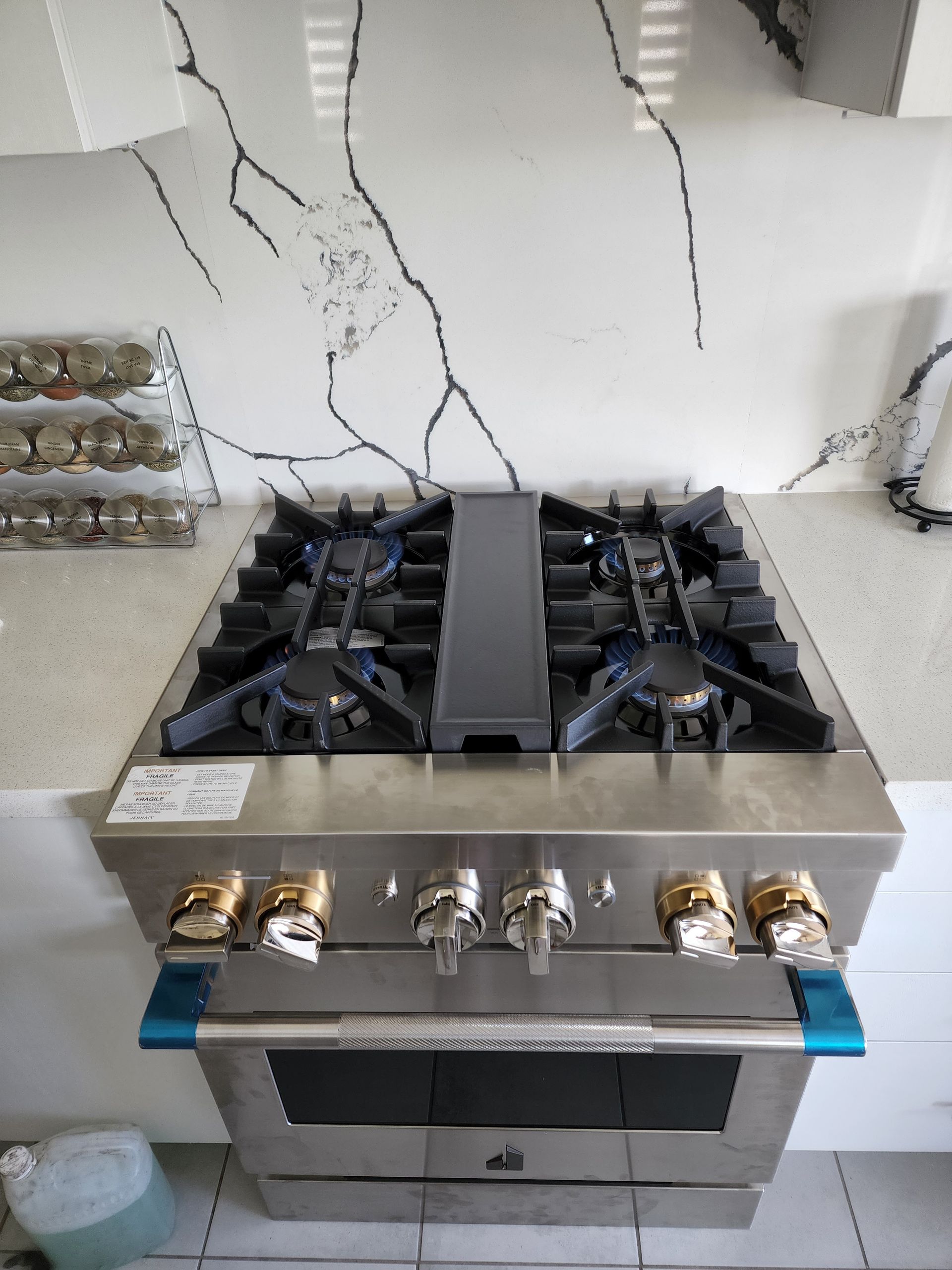 Stainless steel gas range in a white kitchen with a cracked wall behind it.
