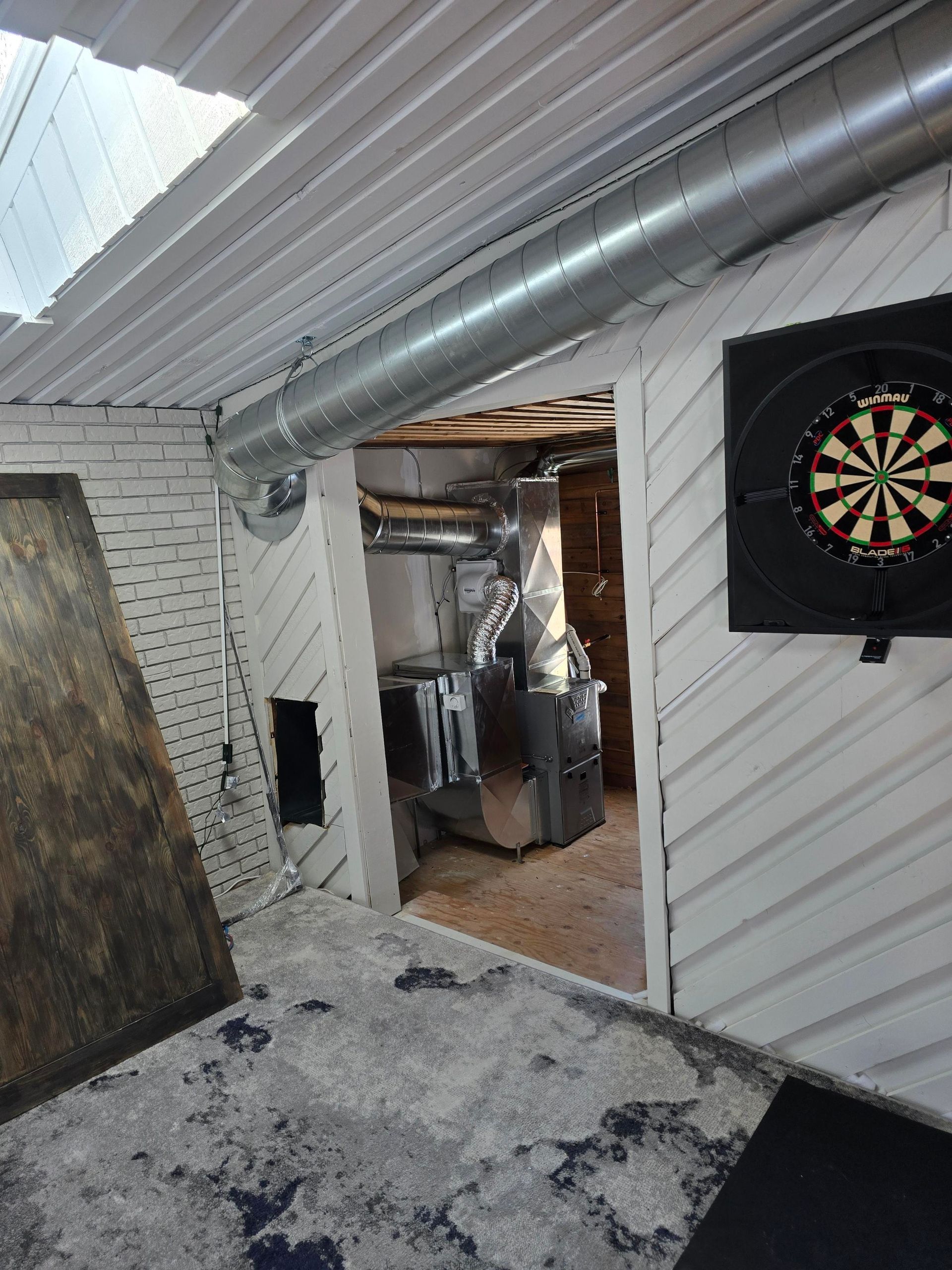 A dart board is hanging on a wall in a basement.