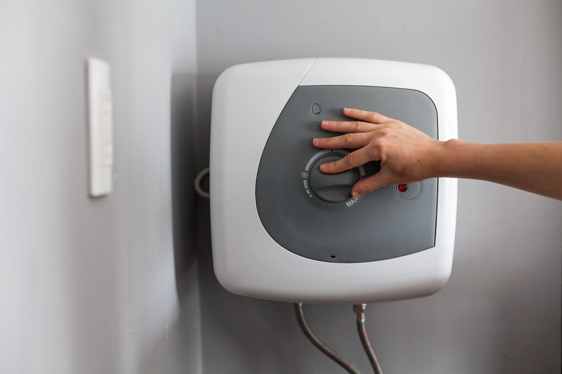 A person is pressing a button on a water heater.