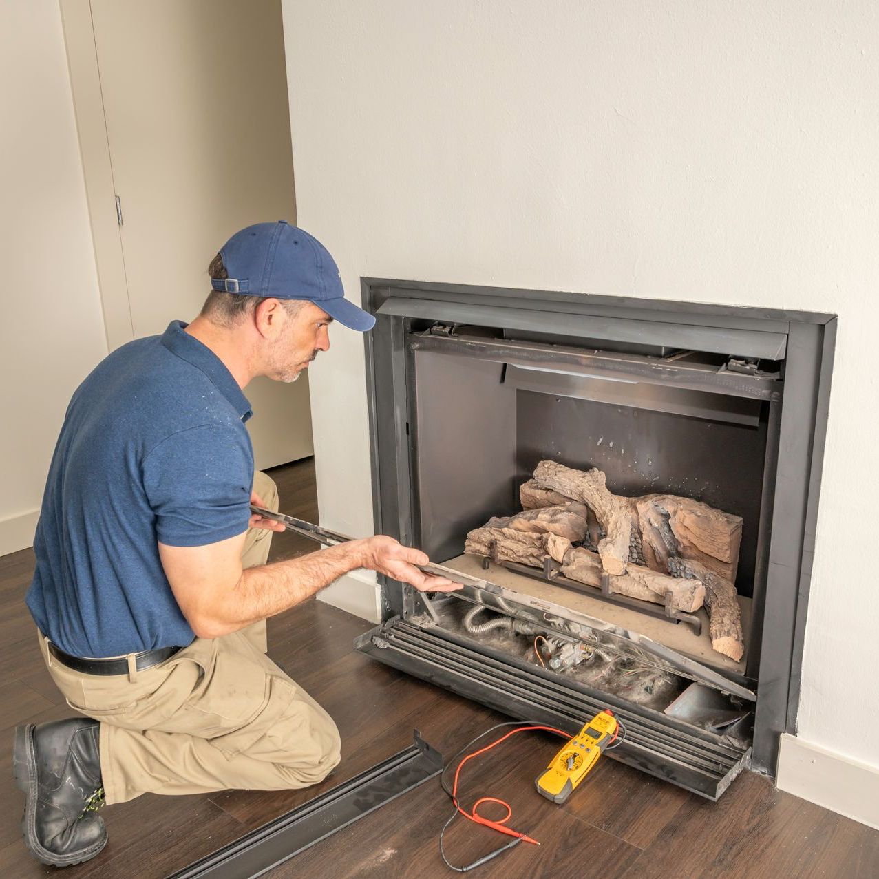 A man is kneeling down in front of a fireplace.