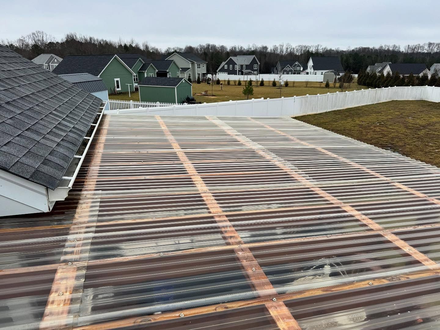 A partially covered roof with corrugated plastic sheets, wooden beams, and a 