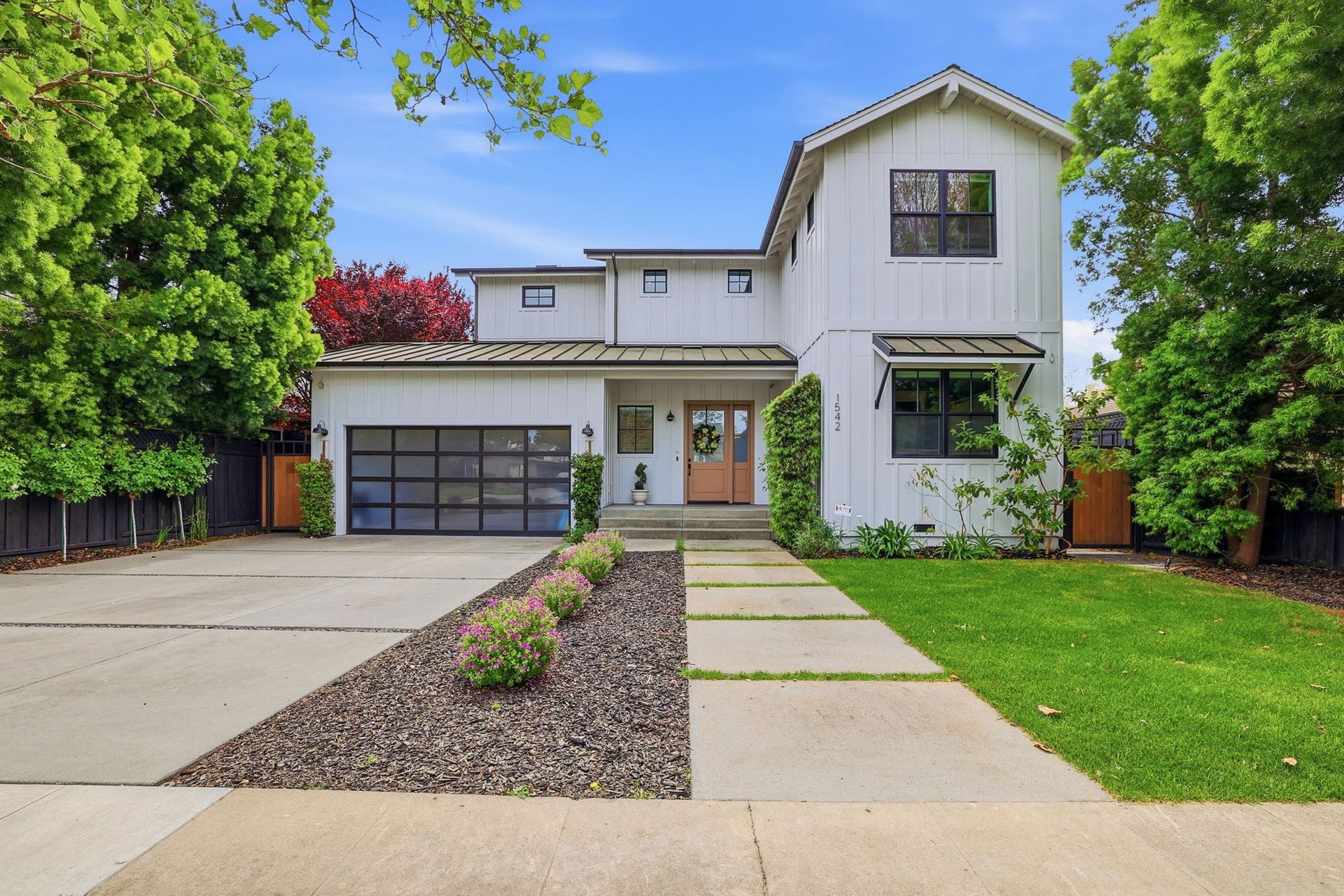Modern two-story white house with a garage, front walkway, and green lawn