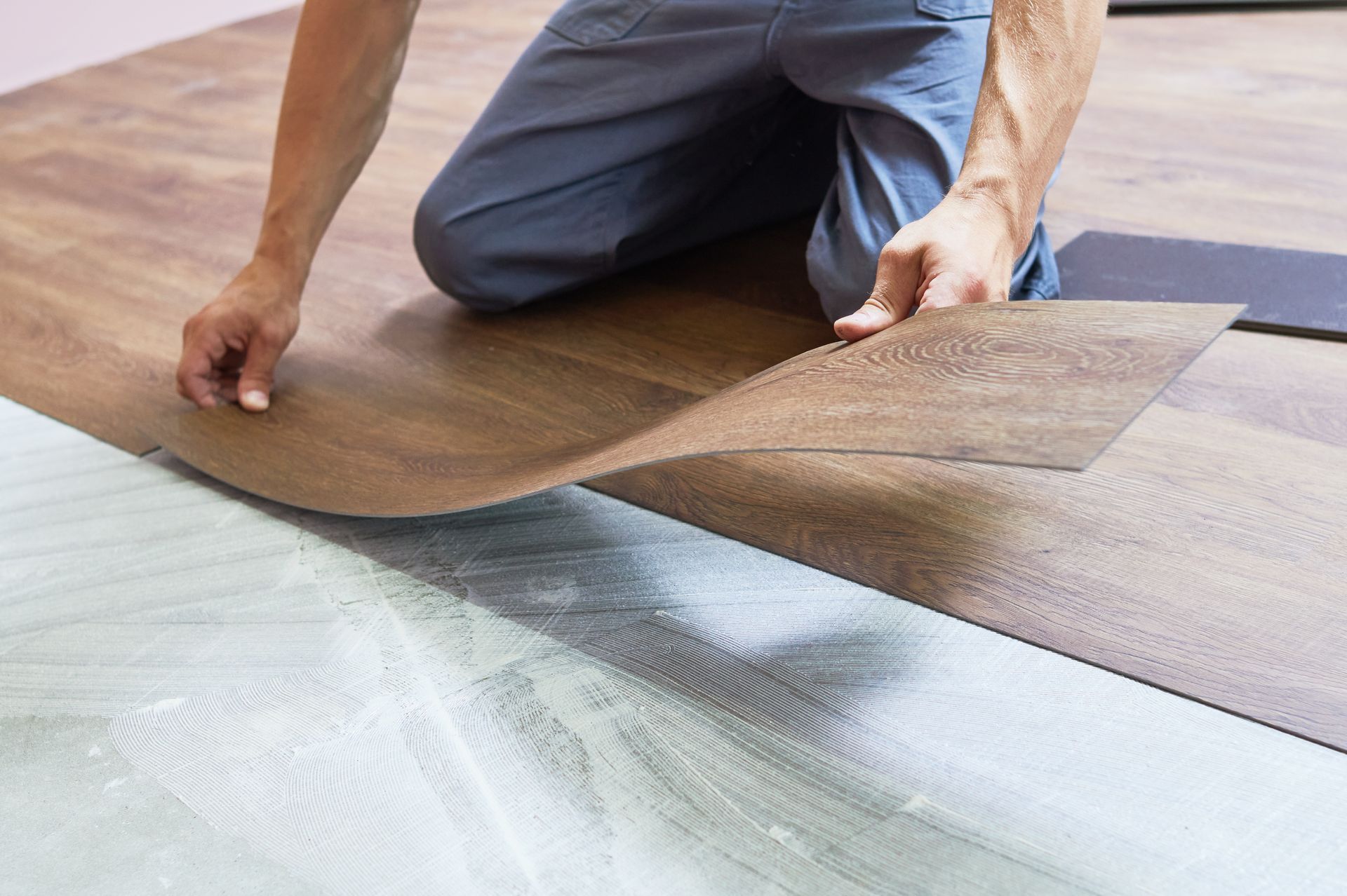 A man is installing a vinyl floor in a room.