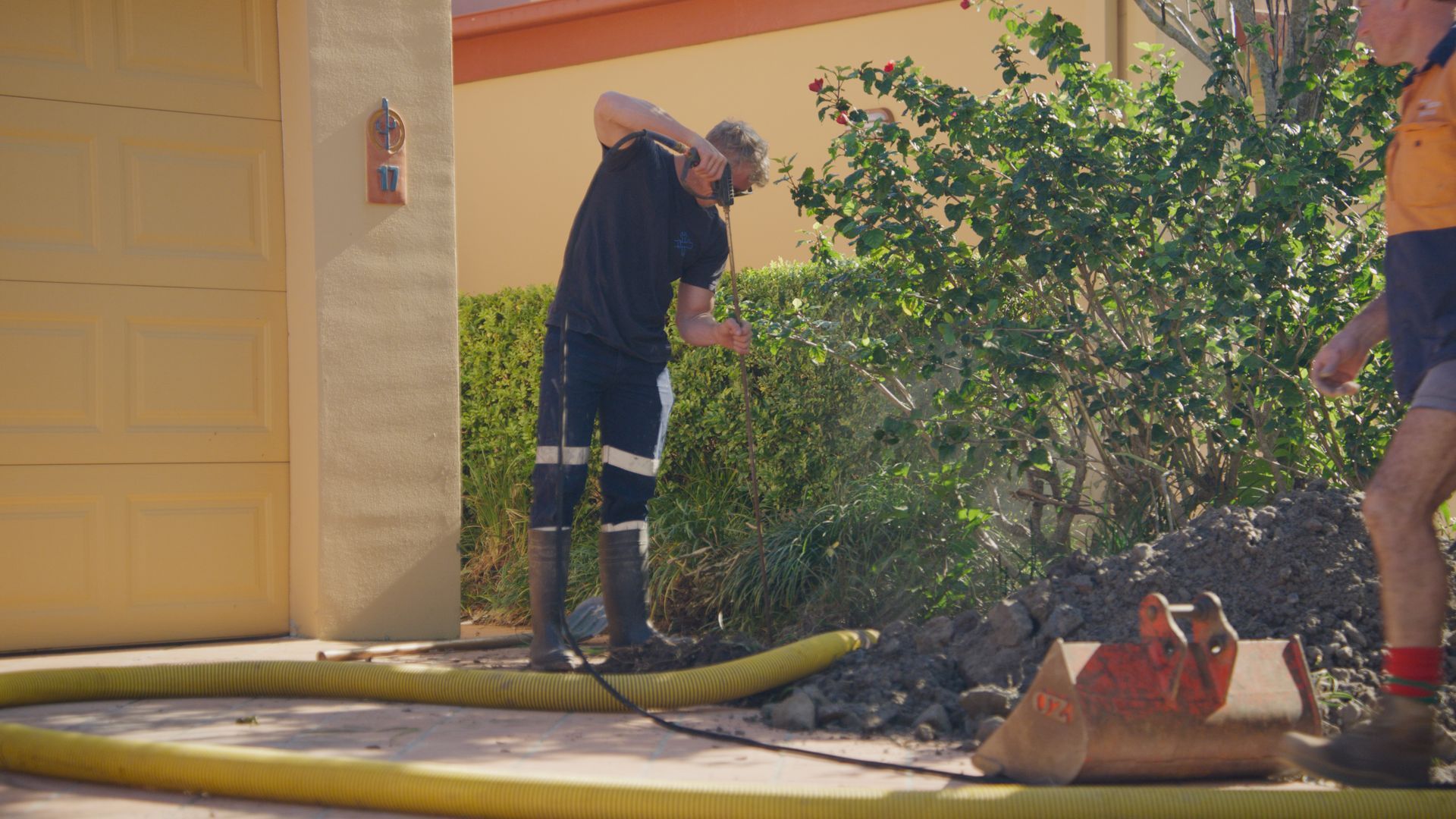 A Man Is Cleaning A Manhole Cover With A Bucket — Tweed Heads Leak Detection in Casuarina, NSW