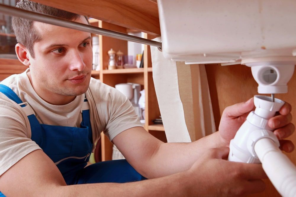 A Plumber Is Fixing A Sink In A Kitchen — Tweed Heads Leak Detection in Casuarina, NSW