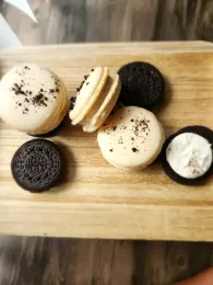 Mini sandwiches with cookie halves and cream on a wooden board
