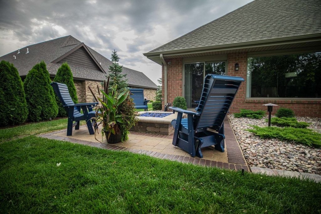 Two blue chairs are sitting on a patio in front of a house.