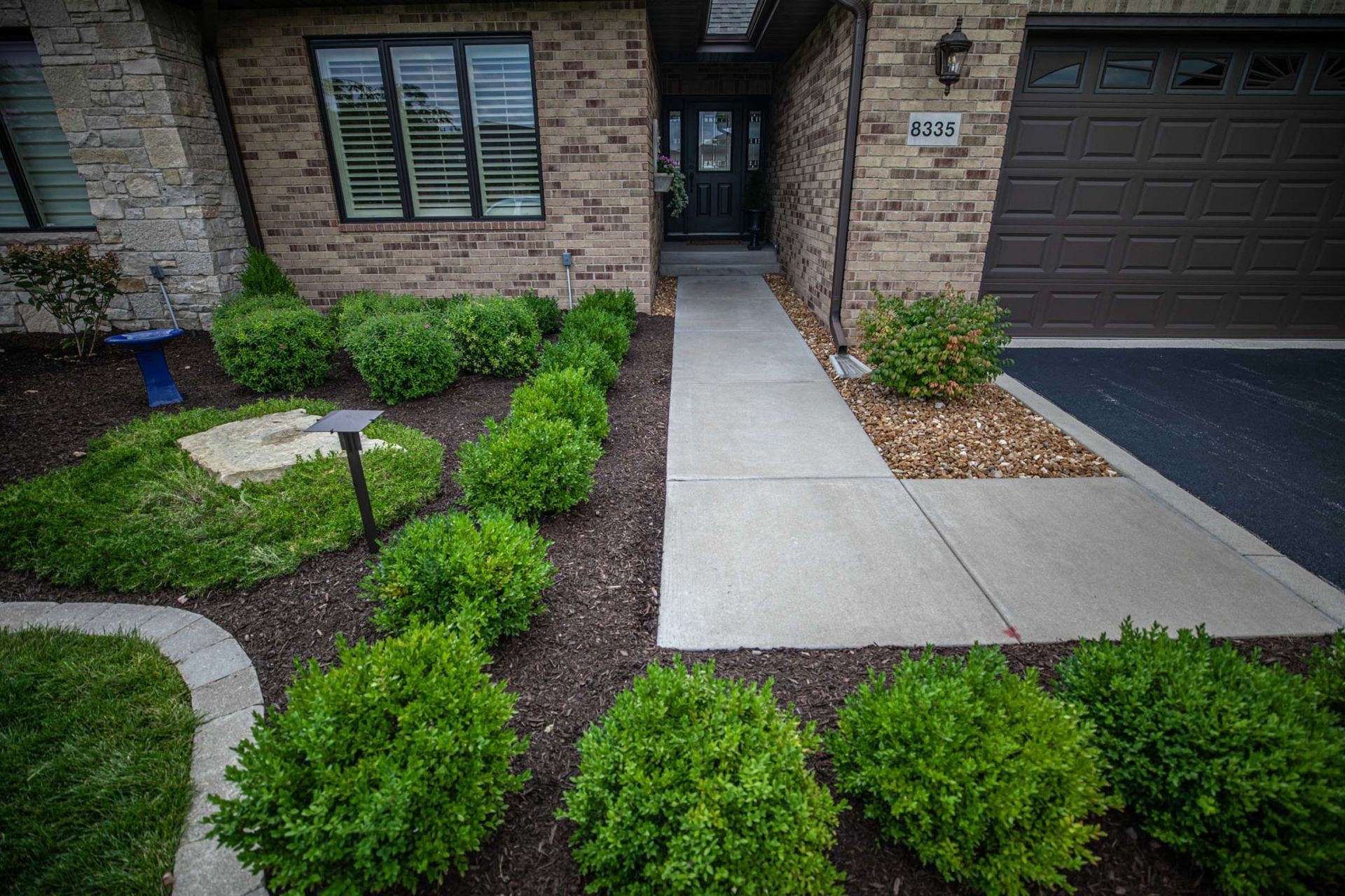 Concrete walkway and mulched shrub beds at a home entry